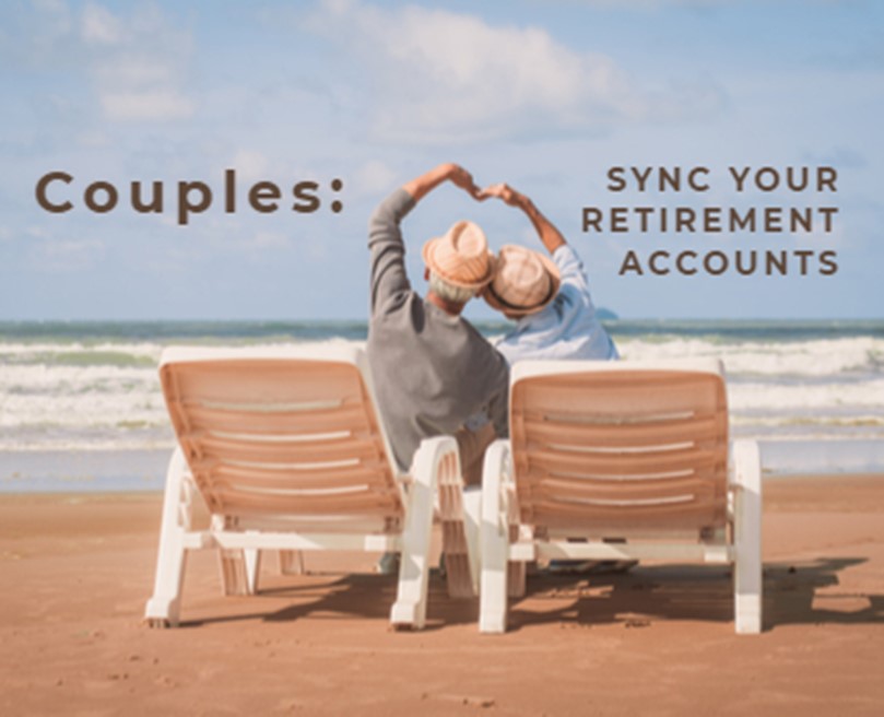 Picture from behind two beach chairs of a couple sitting next to each other making a hear shape with their arms while facing the ocean. Brown text in the blue sky says 'Couples: Sync Your Retirement Accounts'.